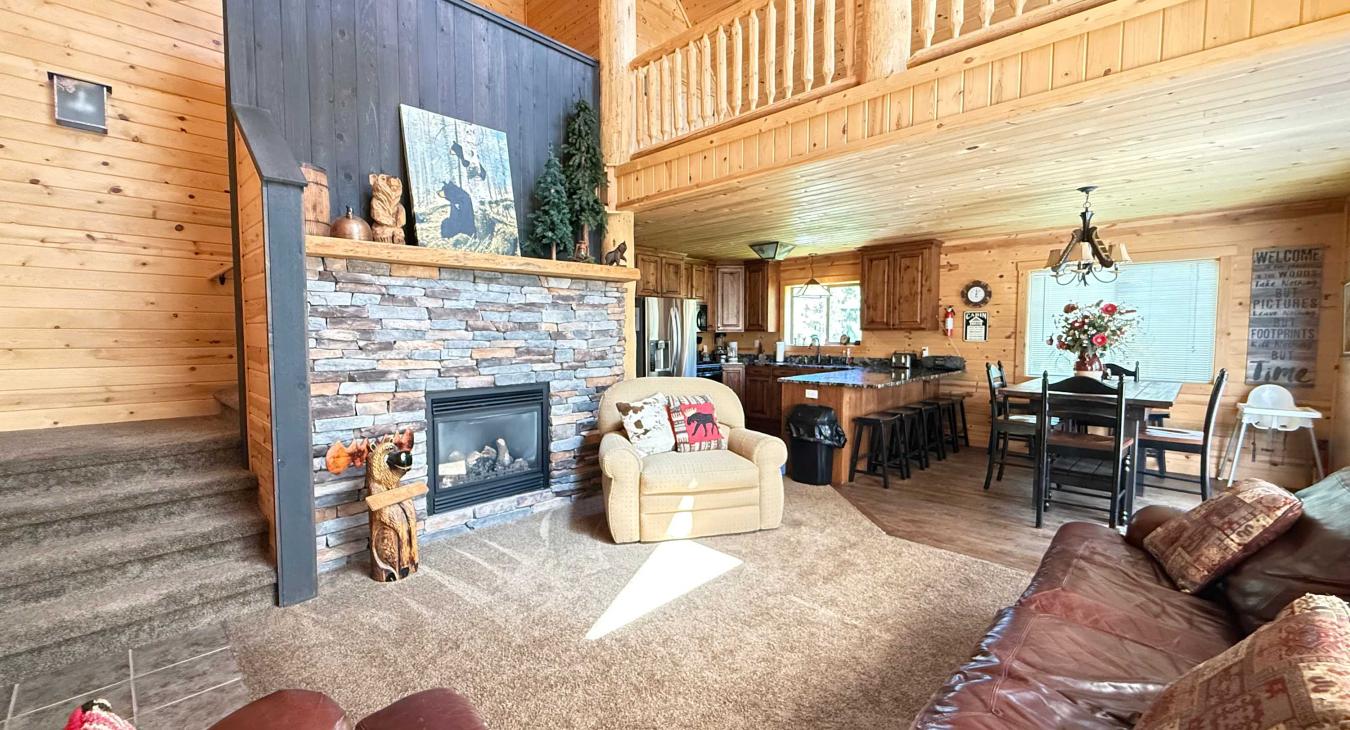 The expansive open-concept main floor features soaring high ceilings, comfortable leather seating, and a grand stone fireplace.
