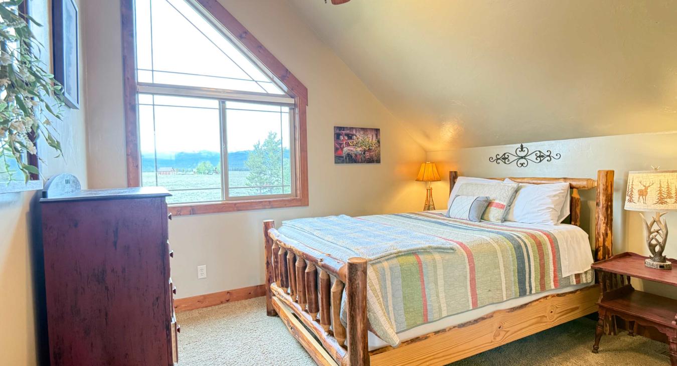 Enjoy peaceful mornings in this cozy upstairs bedroom, featuring a large geometric window that frames the beautiful outdoor scenery.