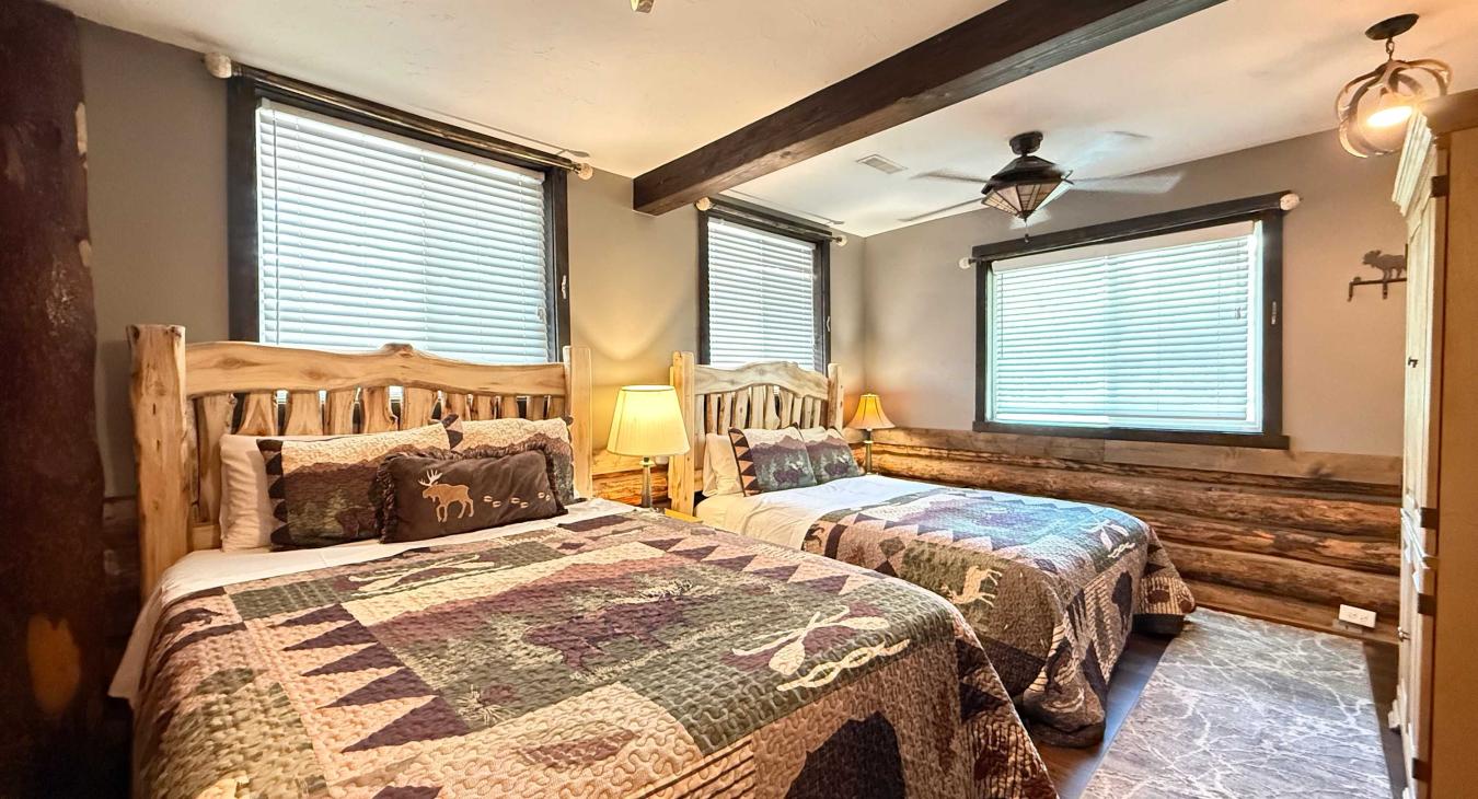 Perfect for families or groups, the third spacious bedroom offers two comfortable log-framed Queen beds side-by-side with cozy matching quilts.