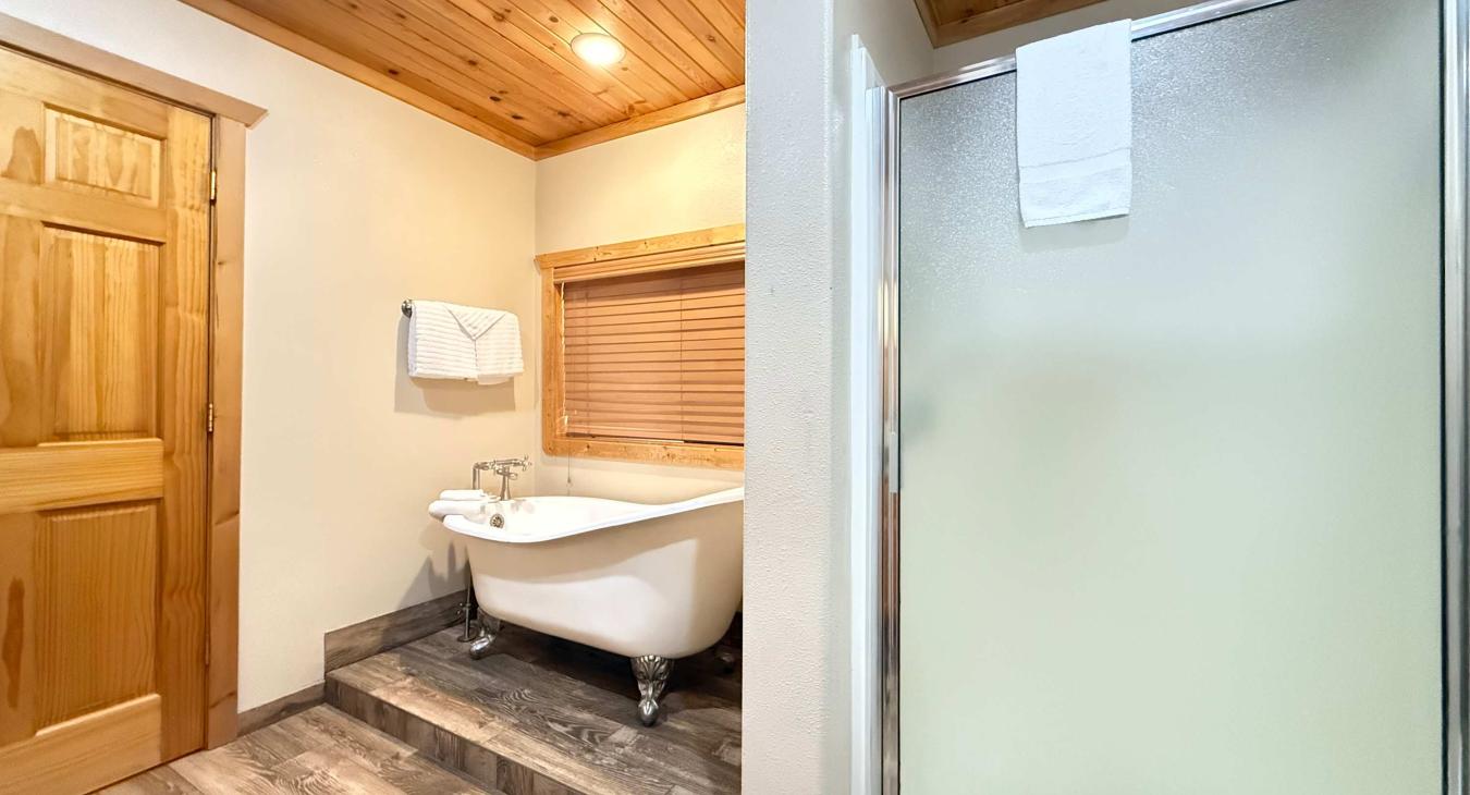 Ensuite bathroom with soaking tub, standing shower, toilet, and sink vanity.