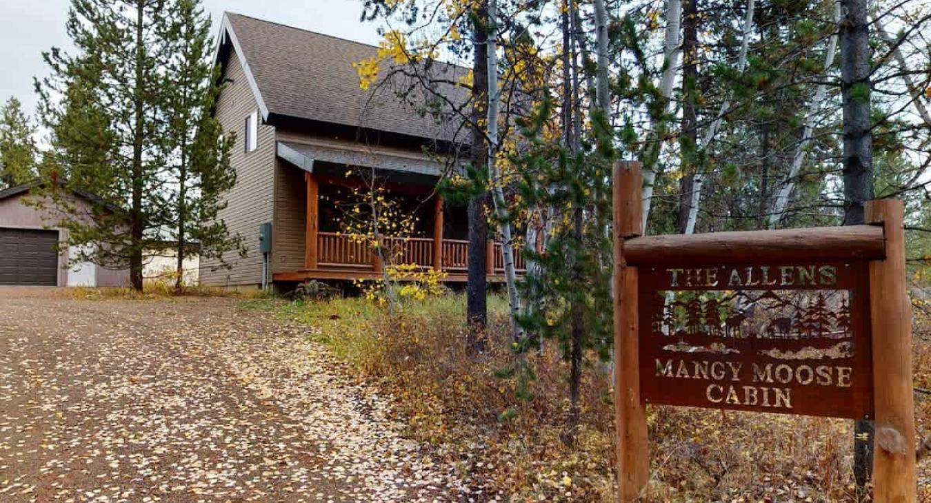Welcome to Mangy Moose Cabin! This private mountain retreat instantly greets you with authentic rustic signage and a scenic driveway nestled in nature.