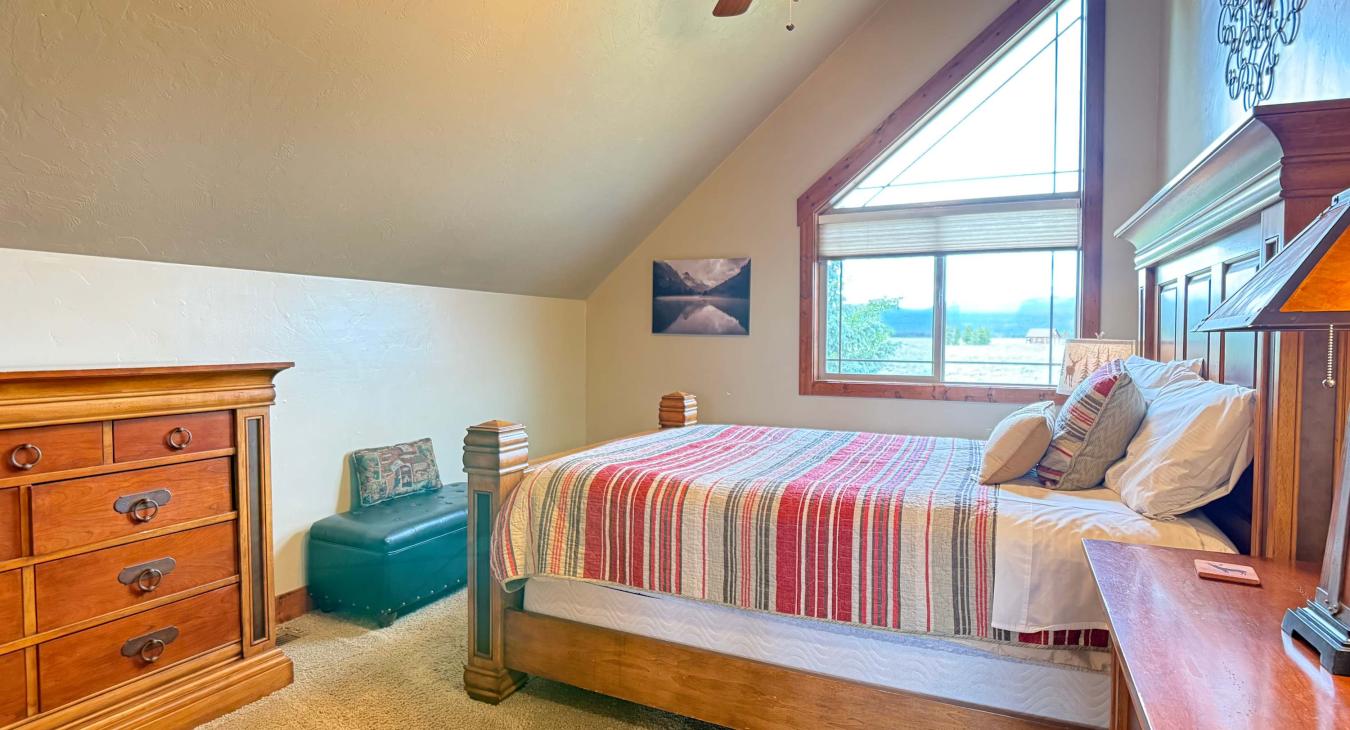 Bright and airy, this upstairs bedroom features vaulted ceilings and a large window that floods the space with beautiful natural light.
