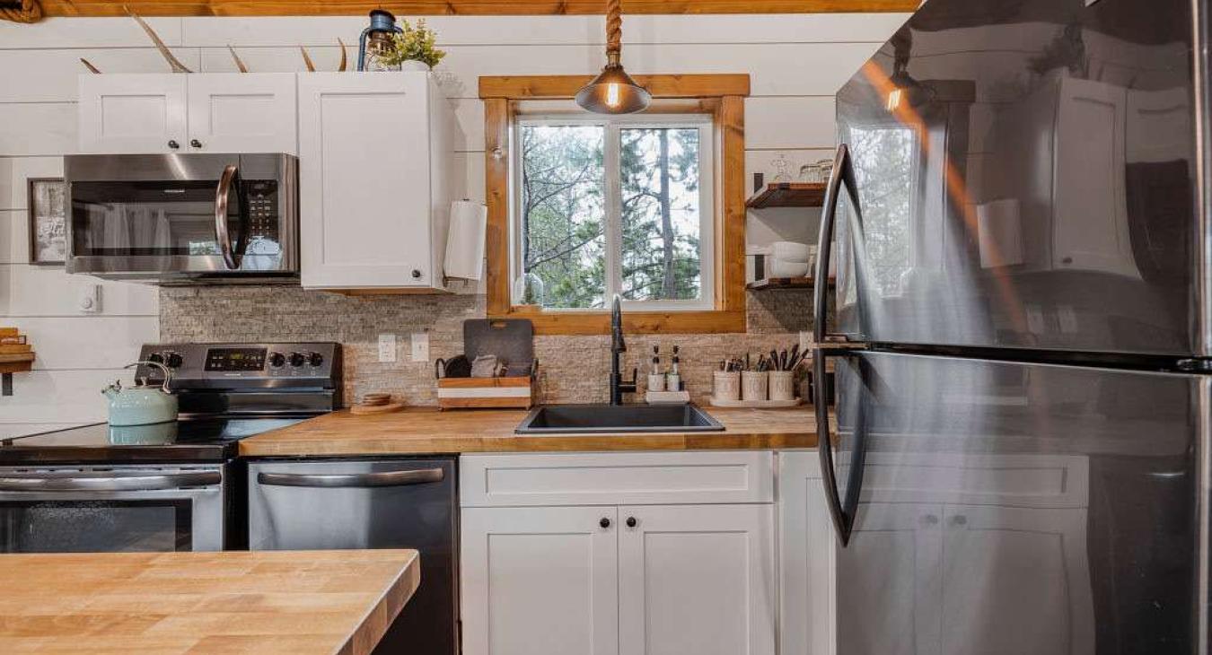 Kitchen with appliances, pots and pans, basic cooking essentials, dishes, and utensils.