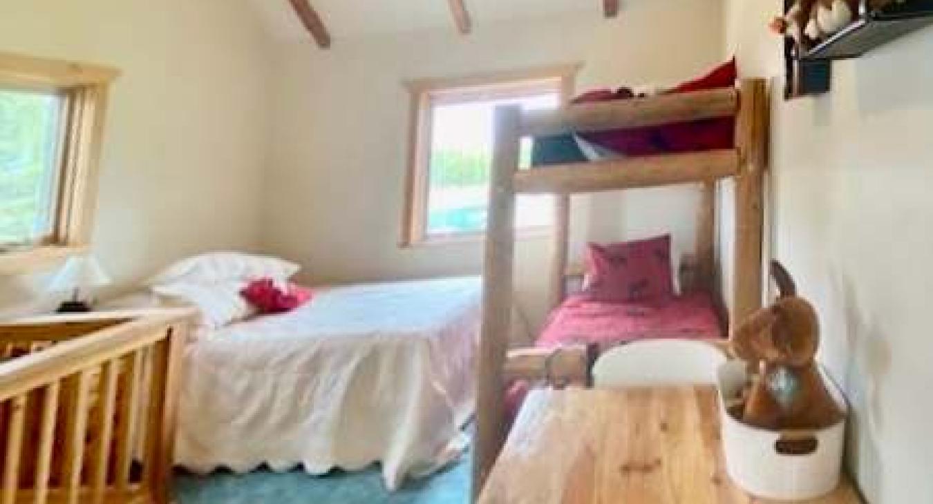 Open upstairs sleeping area with a queeen bed and bunkbed.