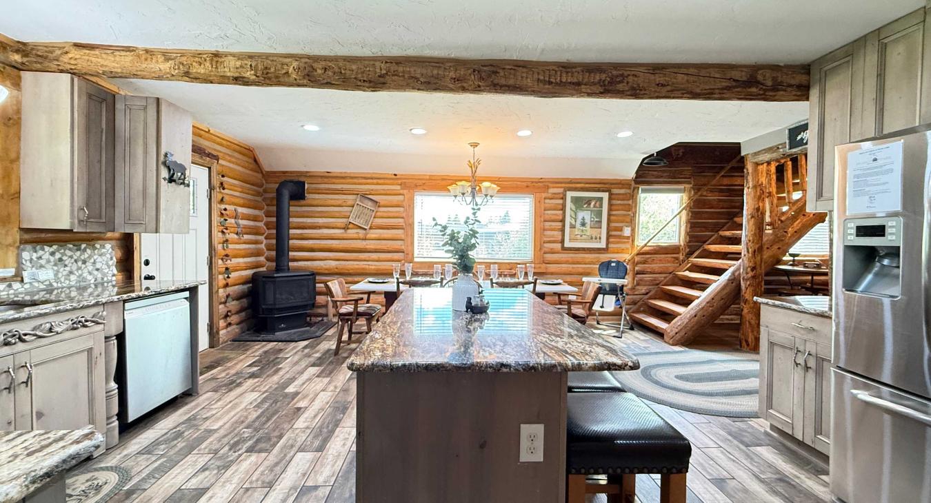 The beautifully designed kitchen blends rustic log charm with modern convenience, complete with high-end stainless steel appliances and smooth hardwood-style flooring.