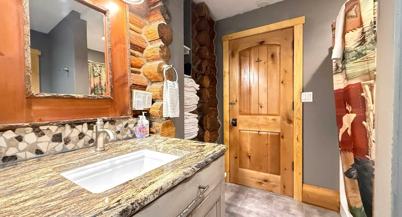 The beautiful 3/4 bathroom features a stunning granite-top vanity with rustic wood framing.