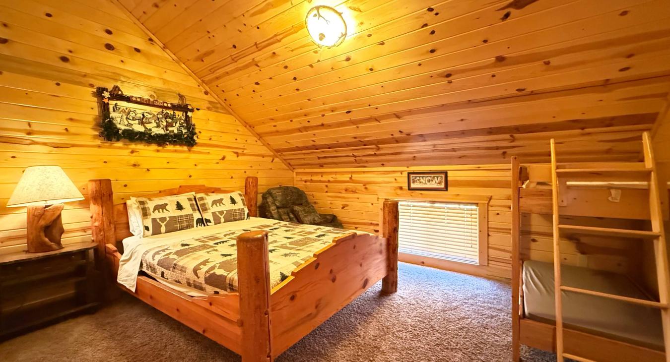 This cozy upstairs bedroom is perfect for families, featuring a sturdy log-style Queen bed paired with a fun wooden twin bunk bed layout.
