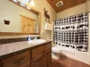 Downstairs full bathroom with shower tub combo, toilet, and double sink vanity.