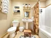 Downstairs bathroom with shower tub combo, toilet, and sink. Towels, shampoo, conditioner, and body wash are provided.