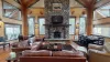 A stone fireplace nestled against a pine-paneled wall, its rough-hewn stones stacked all the way to the vaulted ceiling, with a thick wooden mantel running across the middle like a rustic crown.