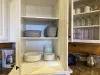 The white kitchen cabinets have a fresh, clean look, offering a modern yet cozy contrast to the rustic charm of the cabin. Neatly arranged, you’ll find a set of glass cups, mugs, plates, and bowls.