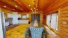Imagine stepping into a warm and inviting dining room in a cabin, where rustic elegance takes center stage. The room is centered around a long, sturdy wooden dining table that stretches across the space. The table is large enough to seat everyone.
