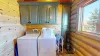 The laundry room in the cabin is a practical yet cozy space that maintains the cabin’s rustic charm. Above the countertop, two wooden cabinets are mounted on the wall, providing ample storage space for laundry essentials.