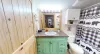 Shared bathroom with a sink vanity, standing shower combo, and a toilet.