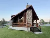 The cabin's exterior is a harmonious mix of natural materials, with large logs and weathered wood giving it an authentic, mountain cabin feel.