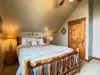 A charming upstairs bedroom nestled under the sloped cabin ceiling, complete with a cozy queen bed and rustic wooden accents.