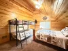 Bright and spacious, this upstairs family room features a clean twin-over-twin bunk bed alongside a matching log-framed bed setup.