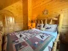 Designed for ultimate group comfort, this sprawling guest suite showcases a master-crafted log Queen bed styled with a rich wilderness quilt and paired with a classic wooden armoire.