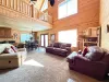 The grand, light-filled living room features soaring vaulted ceilings, a cozy open-loft design, and luxurious leather seating perfect for group conversations.
