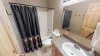 The second bathroom located in the main hallway. With a vanity sink, mirror, toilet, and shower tub combo.