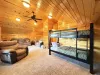 Upstairs loft with a single on single bunk bed with a smart tv and electric fireplace along with seating.