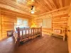 Unwind in the cozy master bedroom, showcasing a rustic log-framed King bed, beautiful all-wood paneled walls, and a charming wooden bench.