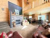 The expansive open-concept main floor features soaring high ceilings, comfortable leather seating, and a grand stone fireplace.