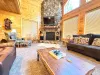 Relax in the grand living room, featuring a magnificent floor-to-ceiling stone fireplace, comfortable plush sofas, and a rustic live-edge coffee table.