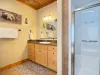 The spacious master bathroom features a beautiful wooden vanity, large mirror, toilet, and a clean, modern walk-in shower.