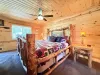 The beautiful master bedroom features an authentic rustic log-framed King bed, a cozy ceiling fan, and warm wood-paneled walls that create a perfect mountain cabin retreat.