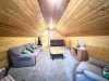 This comfortable garage loft lounge features a cozy sleeper sofa, plush seating, and a TV setup, nestled under beautiful sloped wood ceilings.