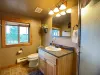 The convenient garage studio bathroom features a beautiful granite-top vanity, large mirror, toilet, and plenty of warm lighting.