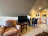 A wonderfully versatile guest suite nestled under sloped rustic ceilings, combining sleep, lounge, and dining options in one massive space.