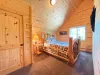 Escape to this cozy upstairs log retreat, featuring a masterfully crafted wood Queen bed beneath towering, dramatic A-frame ceilings.