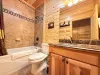 The convenient main-floor shared bathroom offers a beautiful wooden vanity, toilet, and a clean shower-and-tub combo for a relaxing soak.
