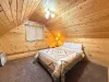Rest easy in the private garage studio queen bedroom, featuring a comfortable bed under warm wood paneling and bright lighting.