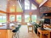 Floor-to-ceiling windows flood the living and dining spaces with natural light, offering beautiful views of the surrounding nature.