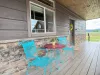 Relax on the charming front porch featuring bright turquoise seating and a small table—perfect for enjoying your morning coffee.