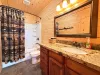 The convenience of an upstairs full bathroom—featuring a sparkling tub-and-shower combo, a premium granite-top vanity with ample storage, and a charming wilderness-themed curtain.