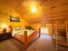 This cozy upstairs bedroom is perfect for families, featuring a sturdy log-style Queen bed paired with a fun wooden twin bunk bed layout.